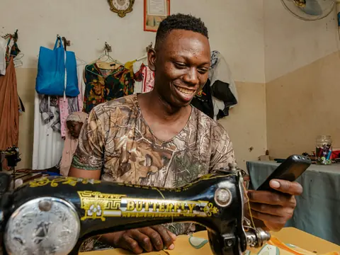 Sastre sonriendo en su taller, junto a la máquina de coser